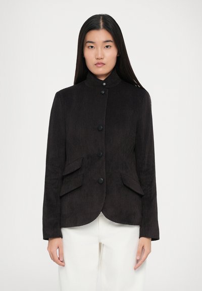 Black corduroy jacket with a mandarin collar, five front buttons, and two angled pockets. Smooth texture, tailored fit, rounded hem.