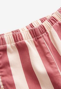 Tissu rayé avec taille élastique, présentant des rayures alternées de rose foncé et de crème. Surface texturée avec des détails de couture visibles.