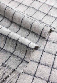 Gray wool blanket with a grid pattern, featuring dark gray lines and fringe edges, showcasing a soft, textured fabric.