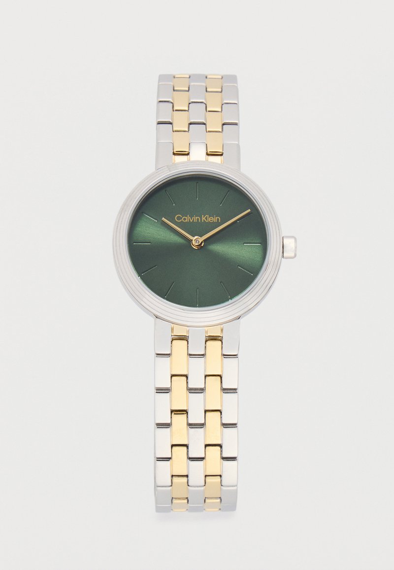 Στρογγυλό ασημένιο και χρυσό μεταλλικό ρολόι χειρός με πράσινο καντράν, χρυσά δείκτες, ελάχιστοι δείκτες ώρας και λογότυπο Calvin Klein στη θέση 12.