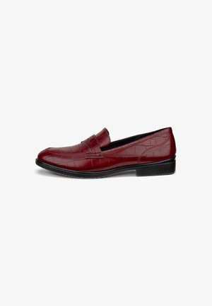 Mocassin en cuir rouge avec texture crocodile, semelle noire et petit talon, présenté de côté sur un fond blanc.