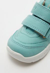 Turkusowe buty sportowe o gładkiej fakturze, z dwoma regulowanymi rzepami, ozdobione subtelnymi przeszyciami i gumową podeszwą.