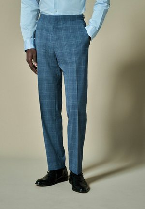 Pantalons à carreaux bleus sur mesure en tissu léger. Comprend des poches latérales et une finition lisse, associés à des chaussures de ville noires.