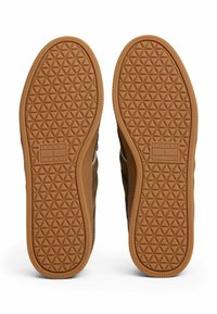 Brauner Sneakersohle mit einem strukturierten Gummi-Muster, das ein Diamantdesign aufweist. Logo im Fersenbereich angezeigt.