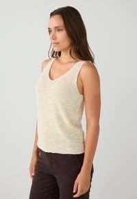Beige gebreide tanktop met een V-hals en brede schouderbanden, met een lichte textuur en een iets getailleerde pasvorm.