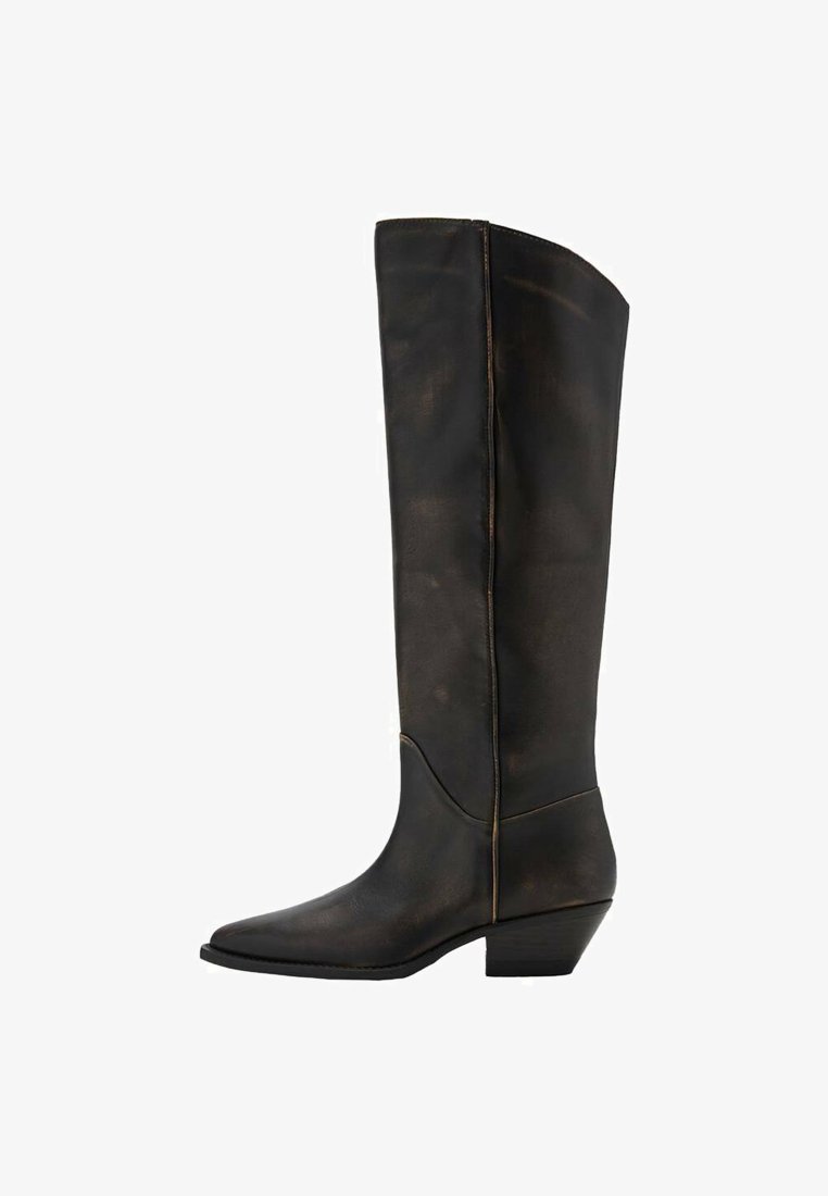Botas altas de cuero negro con puntera afilada y tacón bajo tipo bloque. Presentan costuras visibles a lo largo de las costuras y una textura suave.