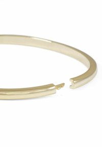 Guldtonad metallarmband med en slät, polerad yta och en liten öppning i ena änden, vilket framhäver dess minimalistiska design.