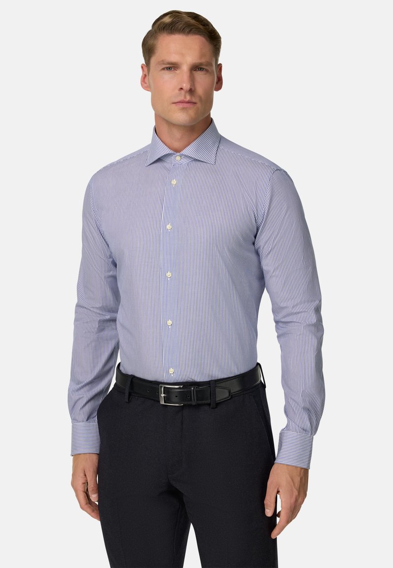 Svetlo modra in bela črtasta srajca z dolgimi rokavi in ovratnikom na gumbe, v paru s črnimi hlačami in črnim pasom. Gladka tekstura tkanine.