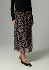 Løveprintet, gennemsigtig maxi-nederdel med en sort elastisk talje. Sammen med sorte flade sko med spænde detaljer.