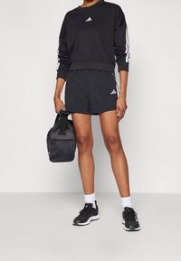 Svart idrottströja med vita ränder, tillsammans med svarta shorts. Inkluderar en liten svart sportväska och svarta löparskor.