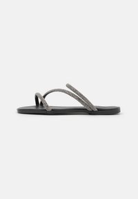 Des tongs noires avec deux sangles métalliques texturées légèrement scintillantes. La semelle est plate et fabriquée dans un matériau résistant.