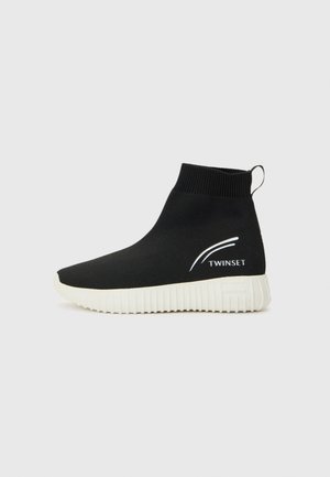 Zwarte gebreide enkellaarsjes met een witte rubberen zool. Beschikt over een logo en een minimalistisch ontwerp. Elastische bovenkant voor eenvoudig aan- en uittrekken.
