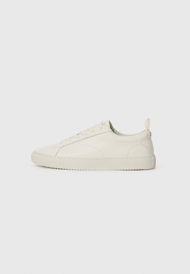 Lys beige lærersneaker med rund tå, snørelukking, minimal søm og teksturert gummisåle. Bakre trekklo er inkludert.