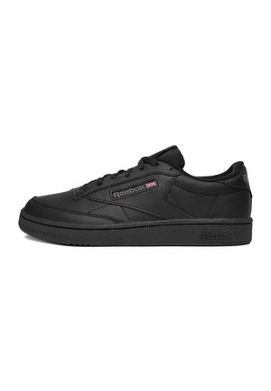 Sneaker Reebok nero low-top con tomaia in pelle, suola nera, lacci e piccolo logo della bandiera britannica sul pannello laterale.