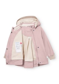 Lichtroze kinderjack met beige fleecevoering, vaste capuchon, geribbelde manchetten en een label aan de binnenkant met was- en materiaalinformatie.