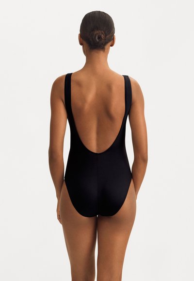 Melnā viengabala peldkostīmā ir platas lences un dziļa aizmugure, izgatavots no gludas, elastīgas materiāla, kas nodrošina ērtumu un piemērotību.