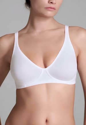 Donna che indossa un reggiseno wireless bianco liscio con spalline sottili, mostrata dalle spalle all'alto addome su uno sfondo grigio uniforme.
