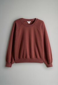 Bordeauxrode trui met een ronde halslijn, raglanmouwen en geribbelde manchetten. Een gladde textuur en een losse pasvorm maken het ontwerp compleet.