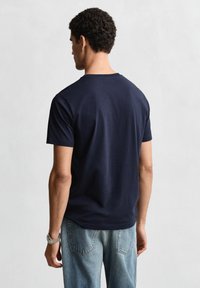 Camiseta de algodón azul marino con cuello redondo y mangas cortas, combinada con vaqueros de mezclilla azul claro. Textura suave; sin patrones o detalles visibles.