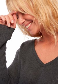 Dunkelgrauer Pullover mit V-Ausschnitt in Strick, mit langen Ärmeln und gerippten Bündchen. Weiche Textur, eng anliegendes Design mit dezenten Nähten.