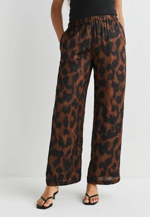 Leopard print wide-leg pants in brown and black, featuring an elastic waistband and textured fabric, with pockets, and a relaxed fit.