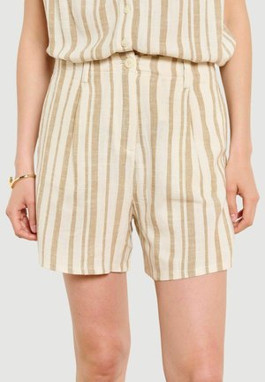 Béžové a biele vertikálne pruhované krátke nohavice s vysokým pásom, predným gombíkom a vreckami, nosené s rovnakým zapnutým tielkom bez rukávov.