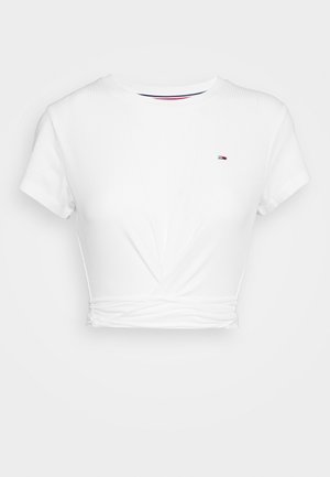 T-shirt blanc court à manches courtes, texture côtelée, col rond et détail de nœud froncé à la taille. Petit logo sur la poitrine.