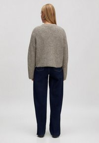 Grijze gebreide cropped trui met ribbelstructuur, wijde mouwen en een rechte zoom, gedragen met donkerblauwe wijde jeans.