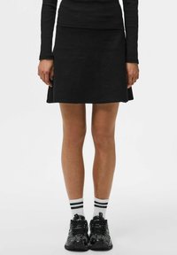 Zwarte gebreide A-lijn rok met een gladde textuur en een schone zoom. Gemaakt met zwarte sneakers en witte sokken met zwarte strepen.
