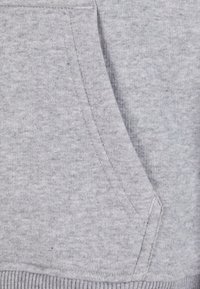 Svetlosivá mikina z látky s mäkkou štruktúrou, so štýlovou klokankou a rebrovaným lemom. Jednoduchý dizajn bez dodatočných vzorov alebo akcentov.