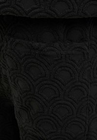 Black fabric featuring a textured pattern of overlapping semi-circles. Includes a visible pocket with stitching detail.
