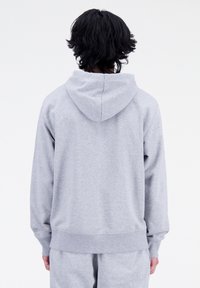 Felpa grigia realizzata in tessuto morbido, con cucitura posteriore, un ampio cappuccio e polsini e orlo a costine per un fit comodo.