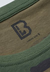 Zöld pamut póló anyag terepmintával; kerek nyakkivágás; fekete logó és méretcímke belül nyomtatva.