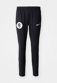 Sorte treningbukser med et hvitt løveemblema på venstre lår og en hvit Nike-logo på høyre side. Laget av myk, stretchy stoff.