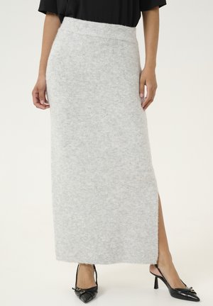 Gray knitted maxi skirt with a high waist, side slit, and soft texture, paired with black pointed-toe heels featuring a buckle detail.