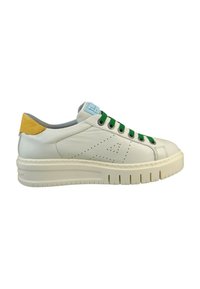 Zapatilla de cuero blanca con cordones verdes, acento amarillo en el talón y diseño perforado. La suela gruesa presenta ranuras horizontales para tracción.