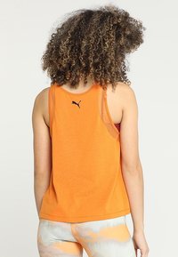 Canottiera senza maniche arancione realizzata in tessuto morbido, con scollatura tonda e un piccolo logo nero Puma sul retro.