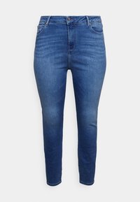 Jeans in denim blu scuro con taglio slim, vita alta, design a cinque tasche e un leggero sbiadimento sulle gambe. Presentano una chiusura con bottone e zip.