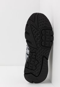 Suela de zapatilla de goma negra con patrones de agarre texturizados, que cuenta con un diseño ligero y un logo de marca prominente.