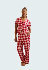 Red and pink checkered pajama set with short sleeves, button closure, and pockets. Soft fabric with a loose fit and casual design.