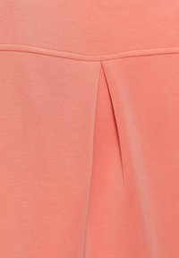 Korallenfarbener Stoff mit dezentem Faltendetail. Glatte Textur mit einem klaren, einfachen Design und kontrastierender Naht am Saum.