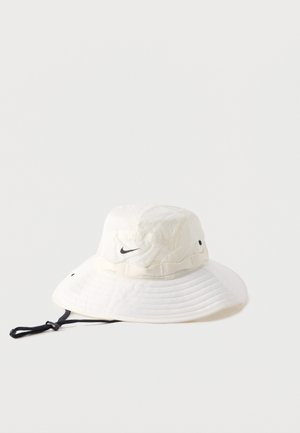 Chapeau bob blanc à large bord avec logo Nike swoosh noir et sangle de menton noire réglable sur fond uni.