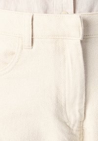 Off-white denim shorts featuring a waistband, front pockets, stitched seams, and a textured fabric with a soft finish.
