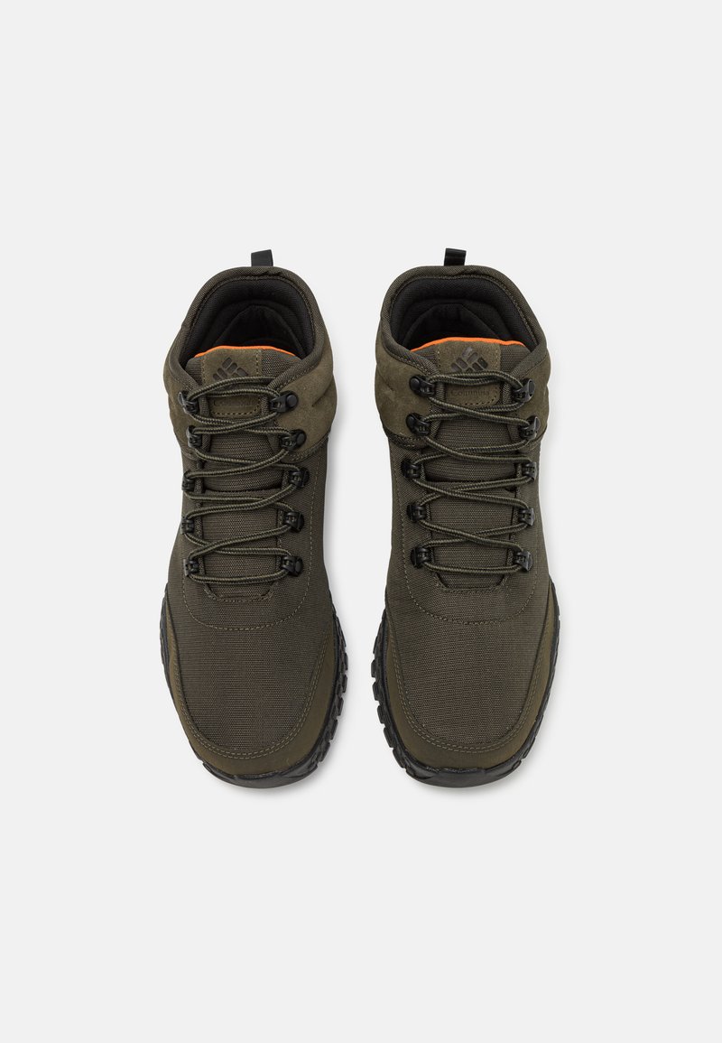 Olijfgroene wandelschoenen met een synthetisch bovenwerk, een gestructureerd oppervlak, vetersluiting, een gevoerd kraagje en een contrasterende oranje binnenkant.