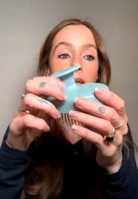 Frau mit langem Haar hält eine hellblaue Haarspange und demonstriert sie vor einem einfarbigen Hintergrund.