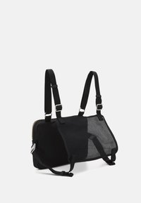 Musta kompakti laukku, jossa on verkkomainen etupinta, kaksinkertaiset säädettävät olkahihnat ja hopeanvärinen vetoketju yksinkertaisella taustalla.