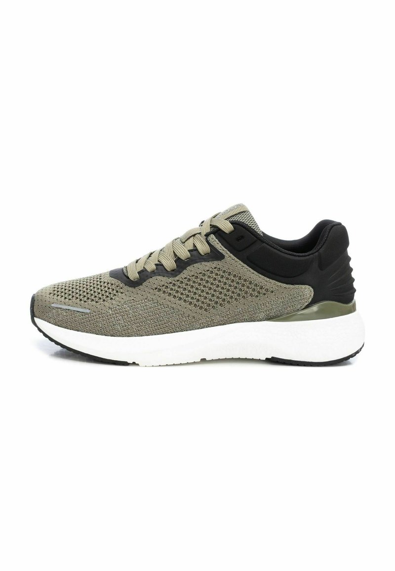 Zapatilla deportiva de malla verde olivo con acentos negros. Presenta una suela blanca acolchada y una suela exterior de goma texturizada. Diseño de cordones.