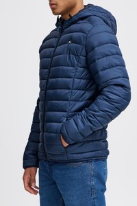 Jachetă puffer de culoare albastru marin cu glugă, având secțiuni orizontale quilted, fermoar complet și buzunare laterale. Textură netedă și lucioasă.