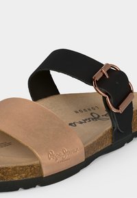 Ανοιχτό πέδιλο με μπράτσο μπροστά σε χρώμα ταμπά, μαύρο ρυθμιζόμενο λουράκι στον αστράγαλο με ροζ χρυσή αγκράφα, φελλό σόλα και μαύρη εξωτερική σόλα.