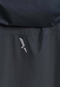 Tissu noir avec un petit symbole d'éclair angulaire gris près d'une couture horizontale et des bords cousus.